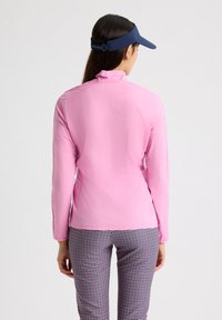 Rosa lätt jacka med långa ärmar, med en stående krage. I kombination med rutiga byxor, har designen minimal synlig hårdvara.