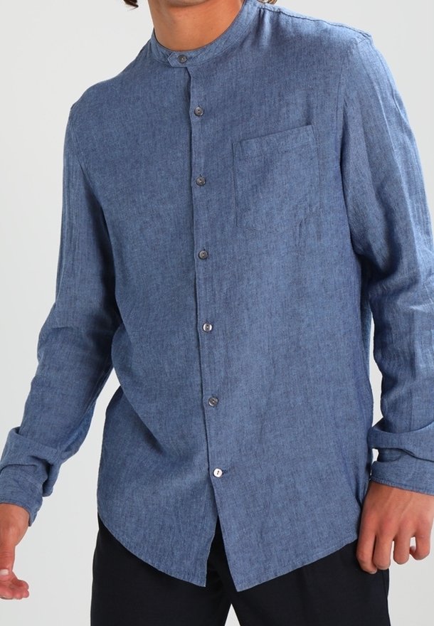 Camicia blu in chambray con colletto a band, maniche lunghe, taschino frontale e chiusura con bottoni. Tessuto liscio e motivo intrecciato sottile in tutto il capo.