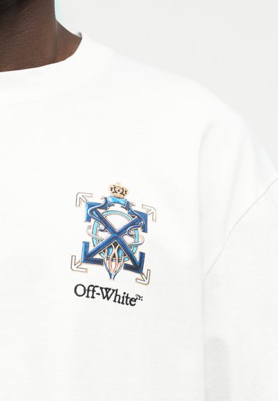Indumento bianco con emblema blu e oro raffigurante frecce, corona e motivo circolare sopra il testo nero "Off-White™" sul petto.