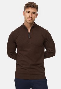 Suéter marrón de manga larga con cuello de media cremallera. Fabricado en un material suave con puños y bajo acanalados. Presenta una textura sutil.