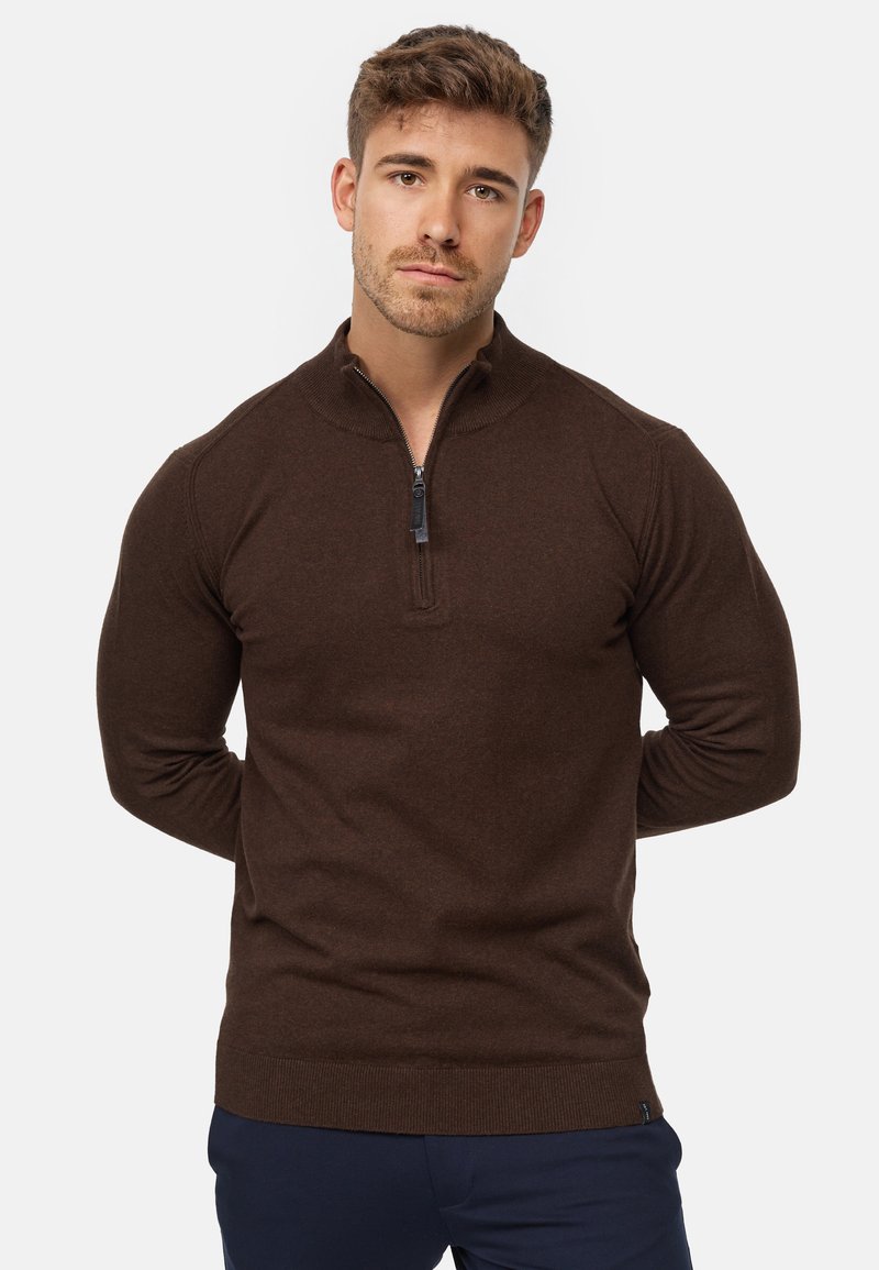 Suéter marrón de manga larga con cuello de media cremallera. Fabricado en un material suave con puños y bajo acanalados. Presenta una textura sutil.