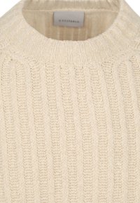 Gebreide trui in lichtbeige, met een geribbeld patroon en een hoge kraag. Het label binnenin de hals zegt "Geschikt".