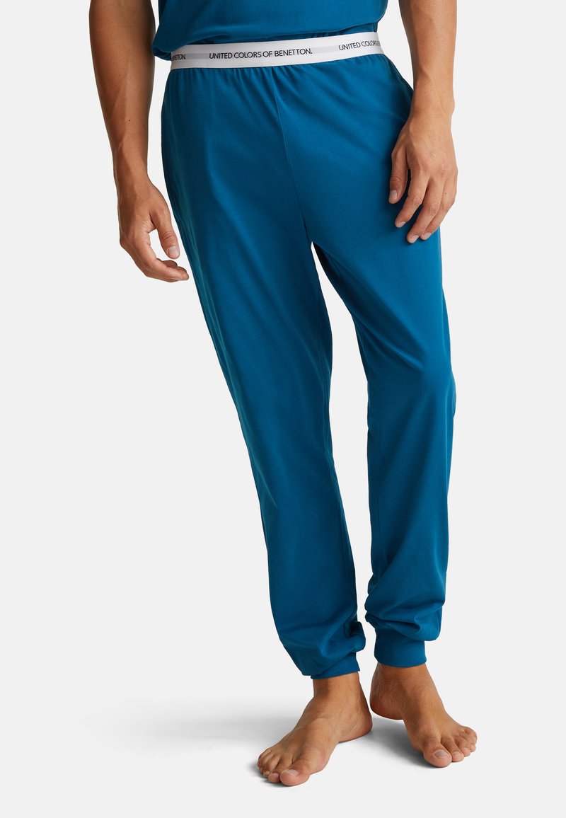 Tyrkysové jogger kalhoty z měkké látky s elastickým pasem označené "UNITED COLORS OF BENETTON." Stahované lemy pro štíhlý střih.