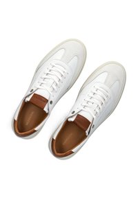 White leather sneakers with a smooth finish, featuring a brown leather accent at the heel, round toe, and lace-up closure.
