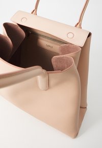 Borsa in pelle rosa chiaro con un esterno liscio e un interno testurizzato. Presenta una tasca con zip sulla parte superiore e due manici morbidi.