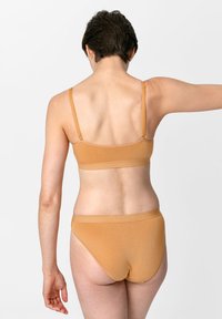 Tan naadloze bh en slipset, met dunne verstelbare bandjes en een gladde textuur, ontworpen voor comfort met een eenvoudige, minimalistische stijl.