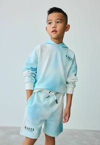 Sudadera con degradado en azul claro y blanco, con un bolsillo frontal y un logo. Combinada con shorts a juego que cuentan con una cinturilla elástica y un logo.