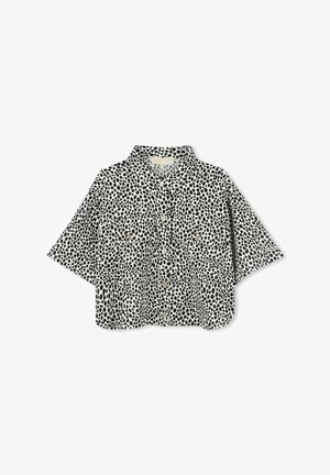 Korte mouwen, colshirt in het wit met een zwart stippenpatroon. Heeft een knoopsluiting aan de voorkant en twee borstzakken. Gemaakt van lichtgewicht stof.