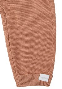 Stickade babybyxor i mjukt, persikofärgat tyg med ett strukturerat mönster. Har ribbade muddar och en vit logotag.