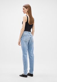 Ανοιχτό μπλε ψηλόμεσα τζιν με χαλαρή εφαρμογή, διαθέτουν σχέδιο πέντε τσεπών και διακριτική φθορά. Συνδυασμένα με μια μαύρη εφαρμοστή μπλούζα με τιράντες.