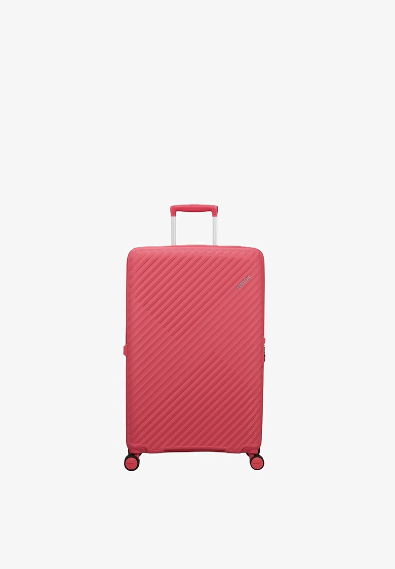 Grande valise rigide rose avec des lignes diagonales texturées, une poignée extensible et quatre roues pivotantes orientées vers l'avant.