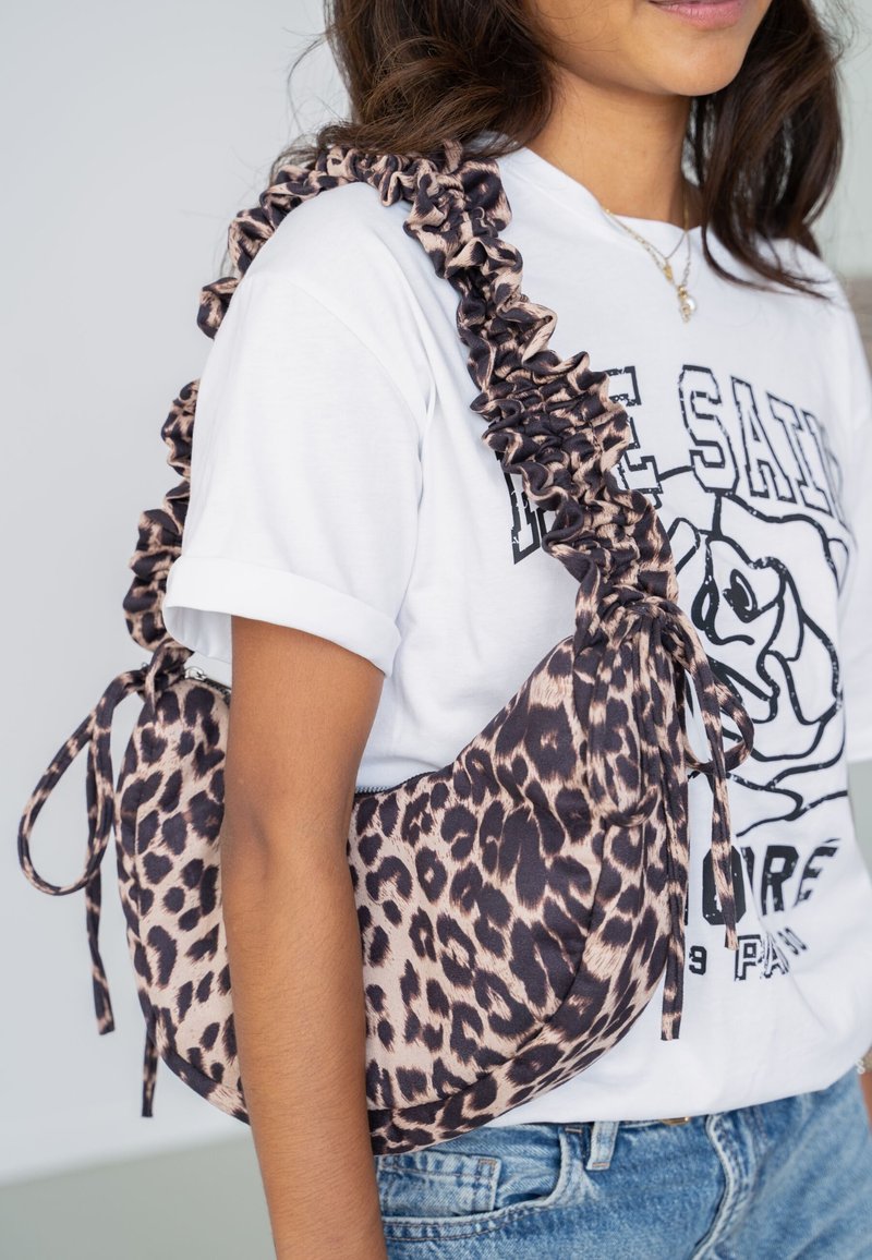 Schoudertas met luipaardprint en een gerimpelde schouderband, gemaakt van zachte stof. Kenmerkt een ronde vorm en verstelbare striksluiting.