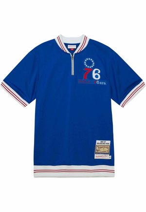 Maillot de sport bleu à manches courtes et col blanc. Présente des rayures rouges, un logo brodé "PHILA 76ers" et un col zippé.