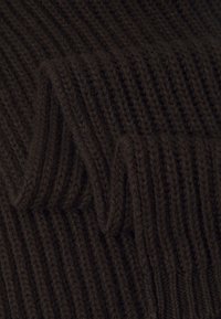 Primo piano di un tessuto a maglia rigata marrone scuro con texture piegata e modelli di cucitura visibili.