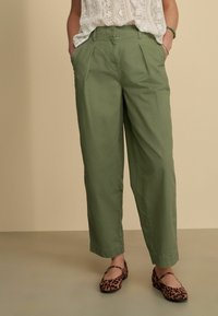 Groene katoenen broek met een losse pasvorm, geplooide voorkant en zijzakken. Gepaarde met bruine flats met panterprint.