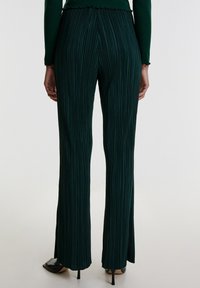 Groene geplooide broek met een uitlopende pijpdesign. Gemaakt van een gestructureerde stof, met verticale lijnen en een tailleband aan de achterkant.