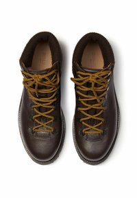 Scarponi da trekking in pelle marrone con lacci gialli, dotati di un design a caviglia alta e un rivestimento interno marrone texture. Suola in gomma con dettagli neri.