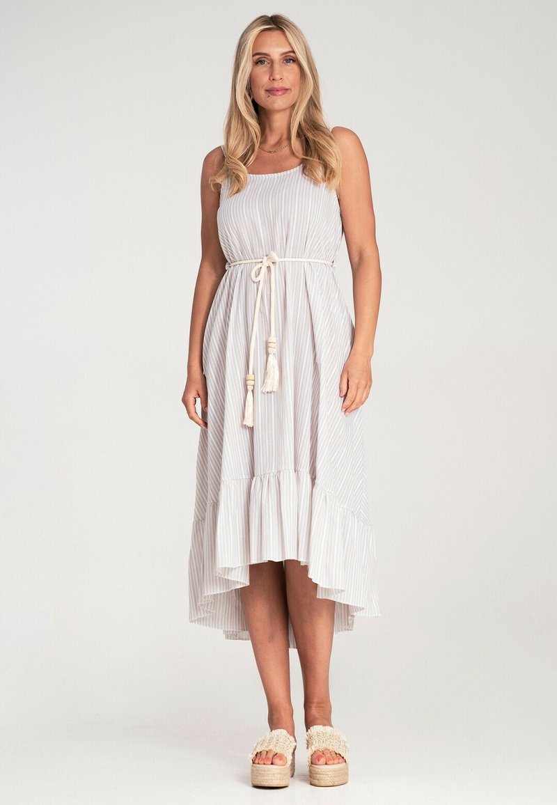 Gestreiftes Maxikleid in hellen Farben mit einem fließenden Saum, Gürtel, der in der Taille gebunden ist, und Quastenakzenten. Getragen mit beigen Plateausandalen.
