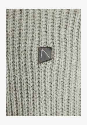 Pilkas megztas megztinis, pagamintas iš vertikaliai raibos medžiagos. Jame yra mažas, stačiakampis juodas odos lopas su baltu logotipu.