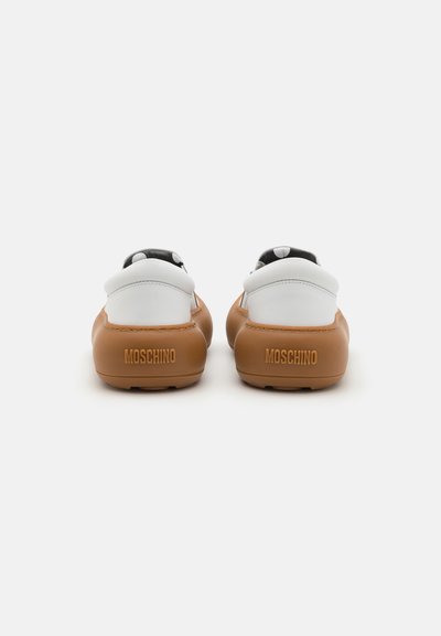 Baskets marron et blanches avec une tige en cuir lisse, bout arrondi et semelle en caoutchouc texturé. Présente le logo "Moschino" en relief à l'arrière.
