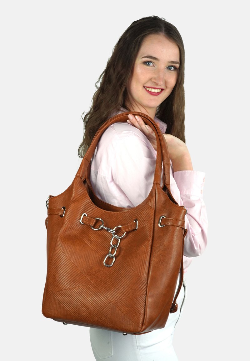 Brązowa skórzana torba typu tote z wzorzystą teksturą, srebrnymi akcentami metalowymi i detalem w formie łańcucha. Posiada mocne ramiączka do noszenia.