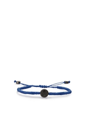Pulsera ajustable trenzada azul con un amuleto circular negro grabado con un símbolo de calavera y huesos cruzados.