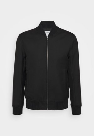 Chaqueta bomber negra con cremallera, cuello, puños y dobladillo acanalados, exhibida sobre un fondo claro y uniforme.