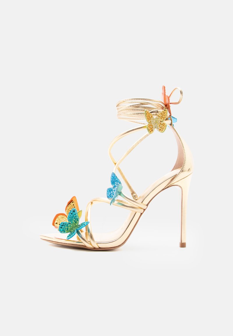 Χρυσό πέδιλο με ψηλό τακούνι, λεπτά λουράκια και πολύχρωμες διακοσμήσεις σε πεταλούδα σε μπλε, κίτρινο και πορτοκαλί σε λευκό φόντο.