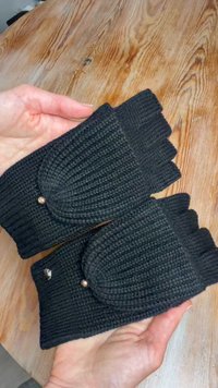 Mustat neulotut sormettomat käsineet, joissa on resorikuvio, pyöreät yksityiskohdat ja kullanväriset metalliosat. Sopivat käytettäväksi kylmään säähän.