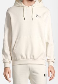 Kremowa bluza z kapturem wykonana z miękkiego materiału, z przednią kieszenią, kapturem ze sznurkiem i logo na lewej stronie klatki piersiowej.