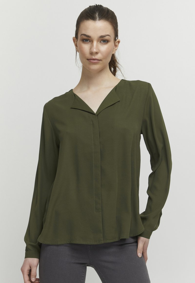 Olive green long-sleeve blouse with a V-neck, featuring a subtle front seam and smooth texture. Lightweight fabric with a relaxed fit.