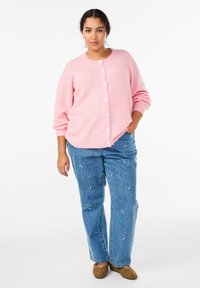 Roza, puhast jopico z okrolim izrezom in belimi gumbi, kombinirano z modrimi džins kavbojkami s cvetličnim vezenjem in ravnim krojem nogavic.