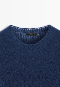 Marineblauwe trui met een ronde hals, gemaakt van zachte, gestructureerde stof. Heeft een fijngebreide afwerking bij de kraag en een zichtbaar merklabel.