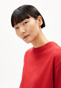 Rode sweatshirt met een ronde hals en geborduurd logo-detail. Zacht materiaal, gladde textuur en een lichtjes ontspannen pasvorm.