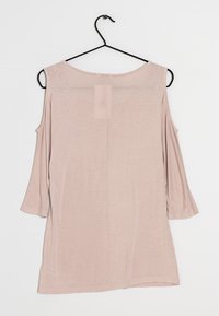 Ljusrosa långärmad topp med axelutskärningar, gjord av mjukt tyg. Har en rundad halsringning och lös passform, hängande p å en svart galge.