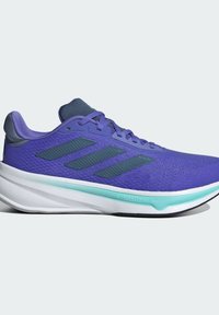Zapatilla deportiva morada con parte superior de malla texturizada, detalles en gris, tres franjas oscuras en el lateral y una entresuela blanca con detalles en aqua.