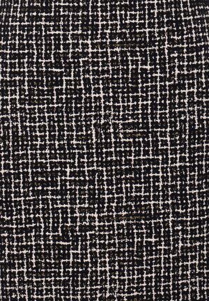 Sort og hvidt tekstureret stof med et spraglet mønster og gyldne accenter, der fremhæver et vævet design og varierende trådtykkelse.