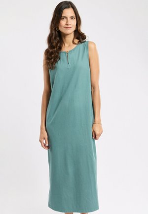 Femme aux longs cheveux foncés portant une robe midi sans manches couleur sarcelle avec un col rond et des boutons à l'avant, debout devant un fond uni.