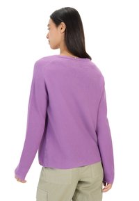 Lilla sweatshirt med lange ærmer og et struktureret strikmønster, med en rund halsudskæring og en syet detalje på ryggen.