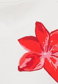 Imprimé floral abstrait rouge et rose sur fond de tissu blanc avec couture visible au bord supérieur.