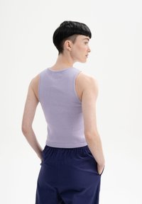 Lila gebreide tanktop met ribbelstructuur en aansluitend ontwerp, gecombineerd met marineblauwe broek met een elastische tailleband en zijzakken.
