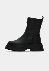 Mustad pahkluu saabas paksu platvormpõhjaga, valmistatud siledast materjalist. Varustatud külgmise tõmblukuga ja tagumise tõmbenupuga hõlpsaks jalapanekuks.