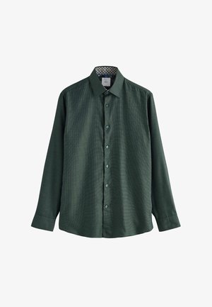 Tumši zaļš garo piedurkņu pogājams krekls ar smalku rakstu, klasisku apkakli un rakstainu iekšējo apkakles oderi, izklāts uz balta fona.