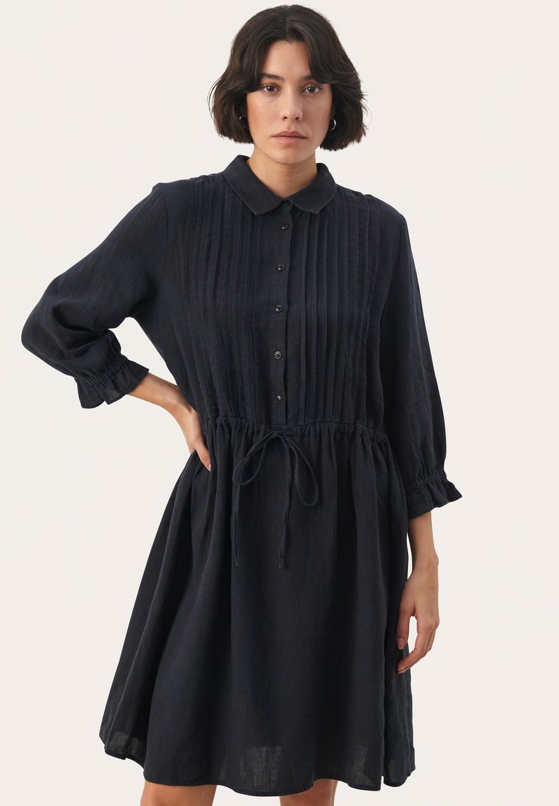 Abito in lino blu navy con colletto a bottoni, corpino plissettato, vita regolabile con coulisse e maniche a sbuffo, progettato per una vestibilità comoda.