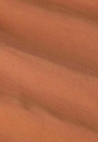 Tissu textile dans une teinte orange chaude et terne avec une texture lisse et un motif de côtes fines en diagonale. Apparence douce et flexible.