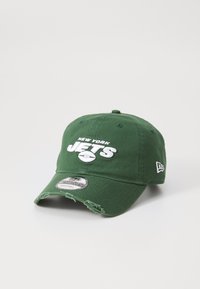 Grønn caps med buet skjerm, med "NEW YORK JETS" i hvit brodering og en fotballgrafikk. Slitt tekstur på skjermen. New Era-merkelapp festet.