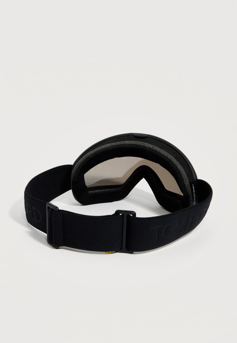 Lunettes de ski noires avec verres teintés et sangle élastique réglable sur un fond blanc.