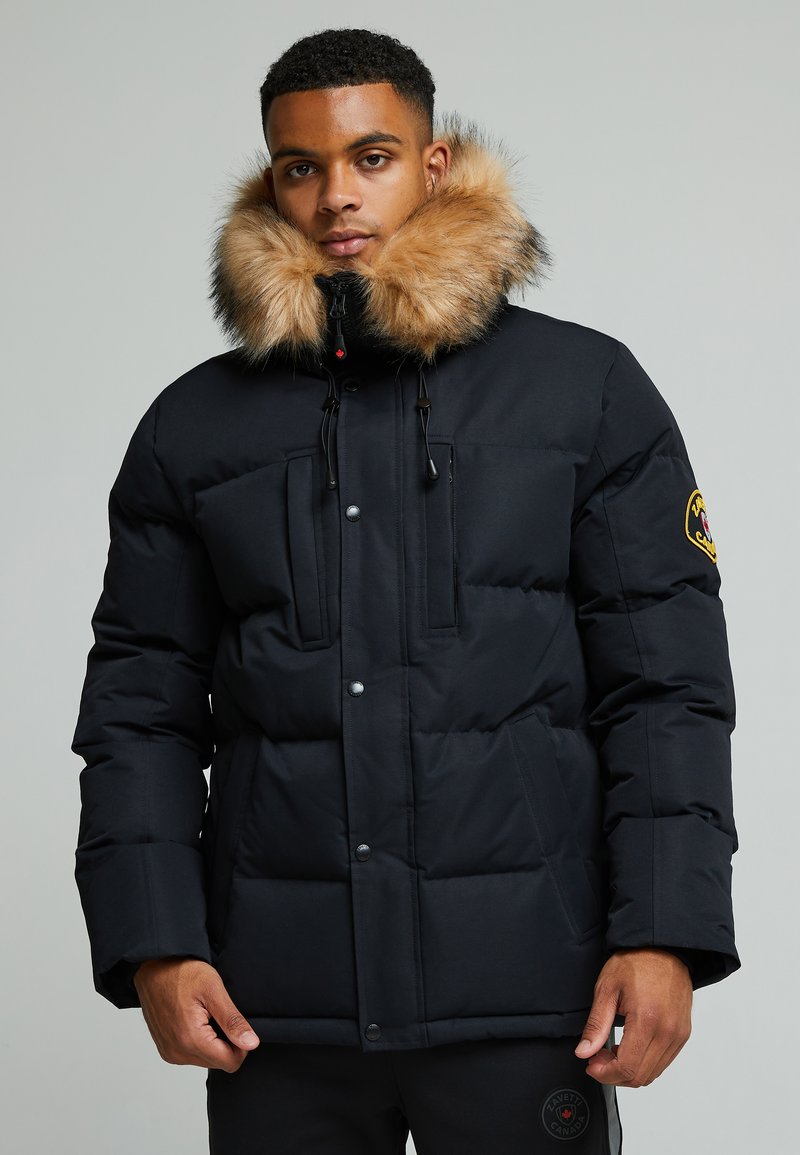 Schwarze Pufferjacke mit einem mit Fell gefütterten Kapuze. Verfügt über zwei Fronttaschen, Druckknöpfe und ein gesticktes Logo am Ärmel. Weiches, isoliertes Material.
