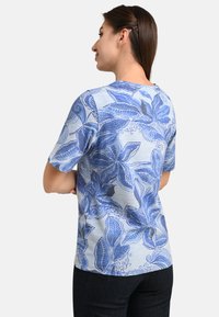Blue floral-patterned T-shirt in lightweight fabric, featuring short sleeves, round neckline, and a relaxed fit against a light background.