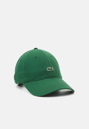 Grønn bomullsbasket cap med buet brem, med en liten brodert krokodillelogo på forsiden.